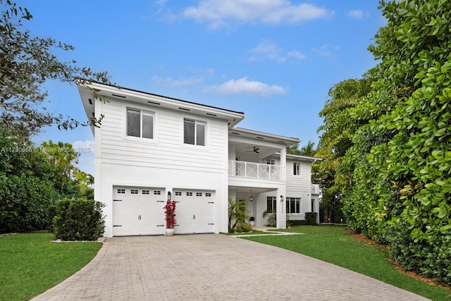 view of front of property with a garage, decorative driveway, a balcony, and a front lawn