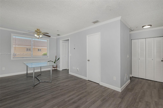 interior space with dark wood-type flooring, ornamental molding, and a textured ceiling