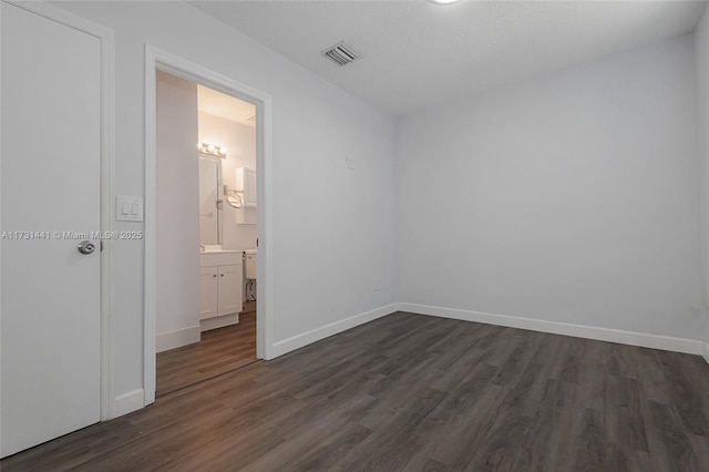 interior space with dark wood-type flooring, ensuite bath, and a textured ceiling