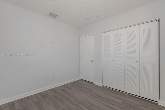 unfurnished bedroom with a textured ceiling, light wood-type flooring, and a closet