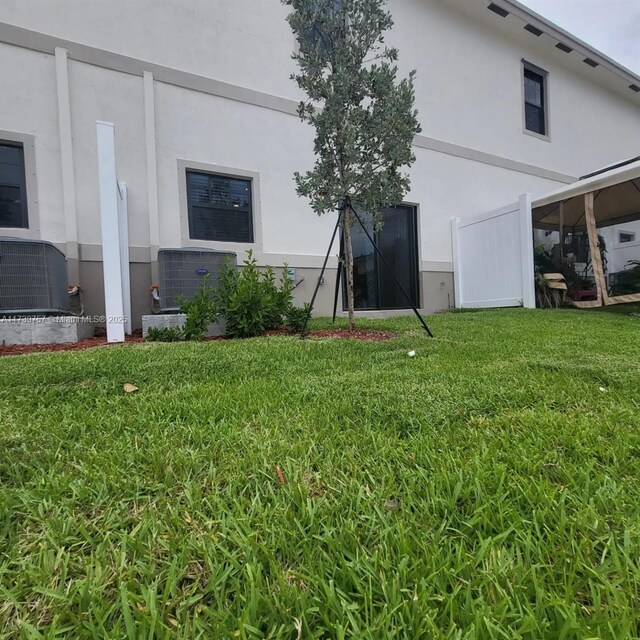 back of property featuring central AC unit and a lawn