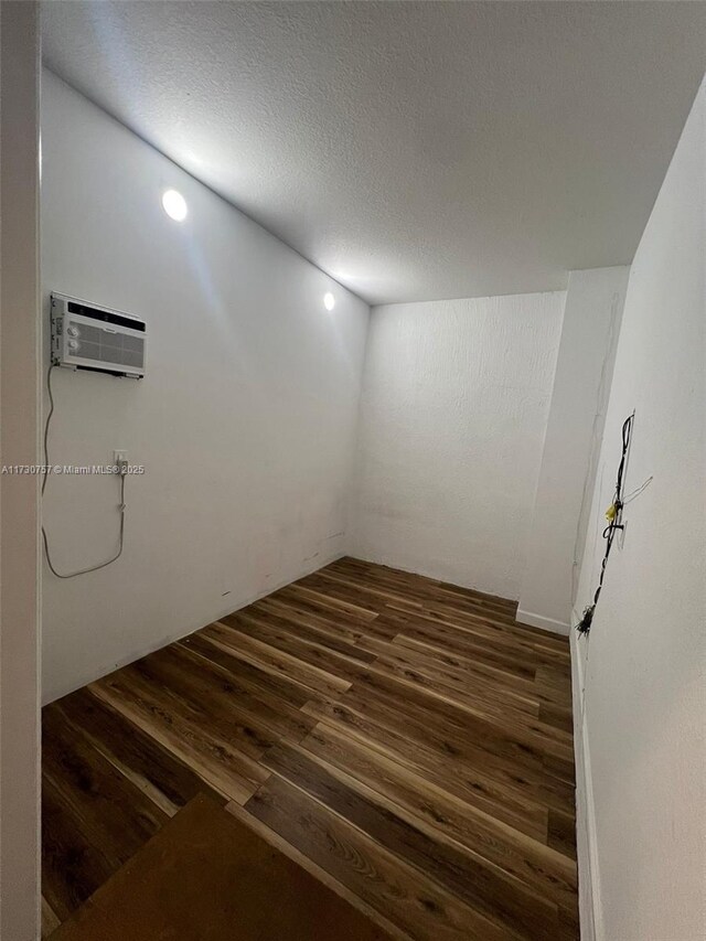 spare room featuring a textured ceiling, dark hardwood / wood-style floors, and a wall mounted AC