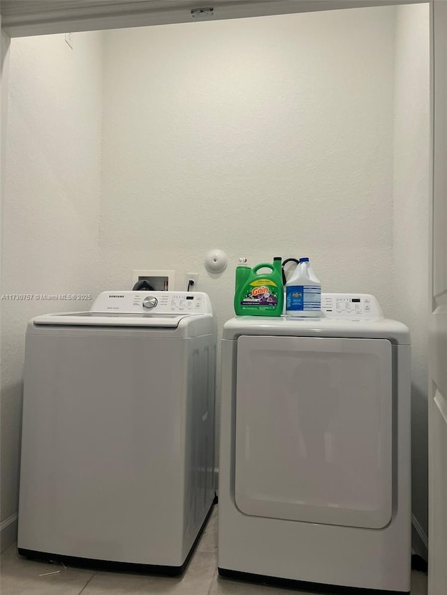 laundry area with washing machine and dryer and light tile patterned floors