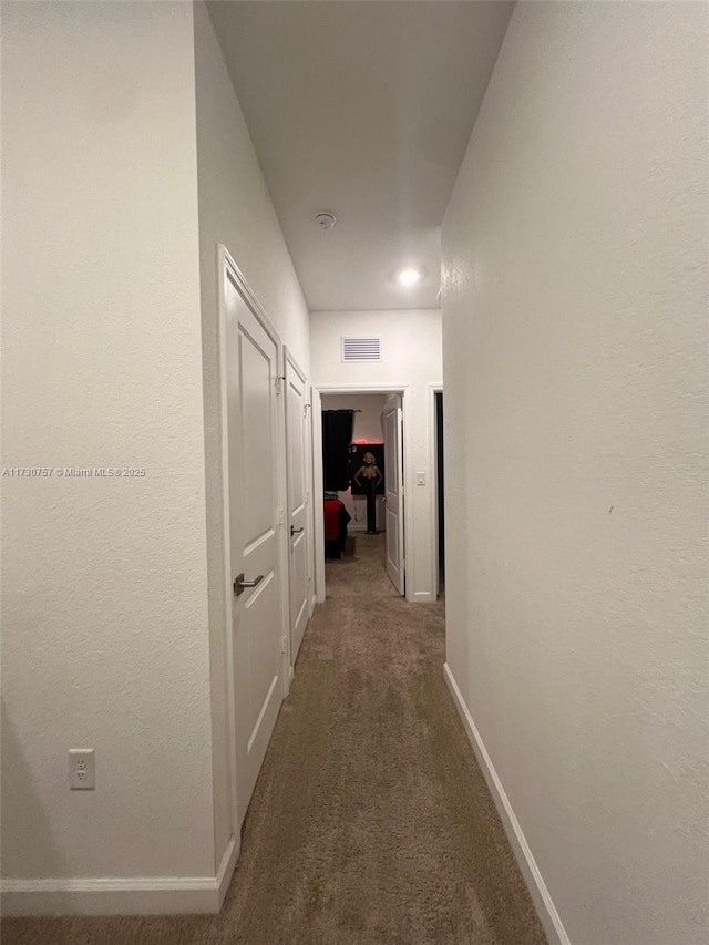 hall with dark colored carpet