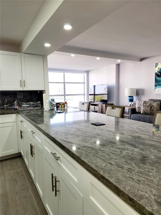 kitchen featuring tasteful backsplash, dark stone countertops, and white cabinets