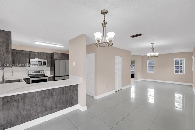 2050 NE 140th St Unit 1, North Miami Beach, FL 33181 - kitchen featuring stainless steel appliances, a chandelier, light tile patterned floors, a sink, and decorative light fixtures
