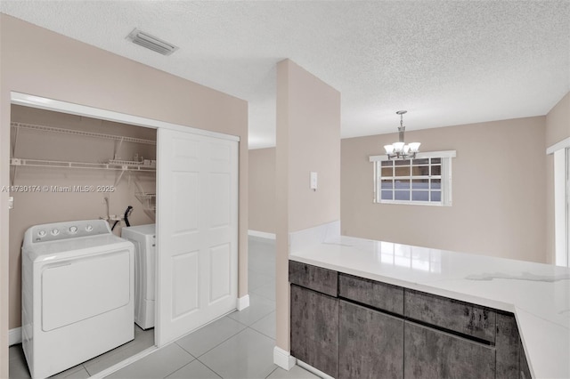 2050 NE 140th St Unit 1, North Miami Beach, FL 33181 - washroom featuring separate washer and dryer, a textured ceiling, a chandelier, light tile patterned flooring, and baseboards