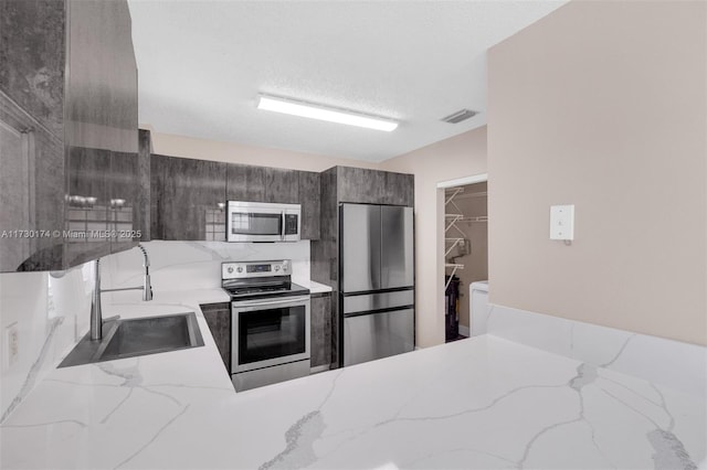 kitchen with appliances with stainless steel finishes, sink, and a textured ceiling