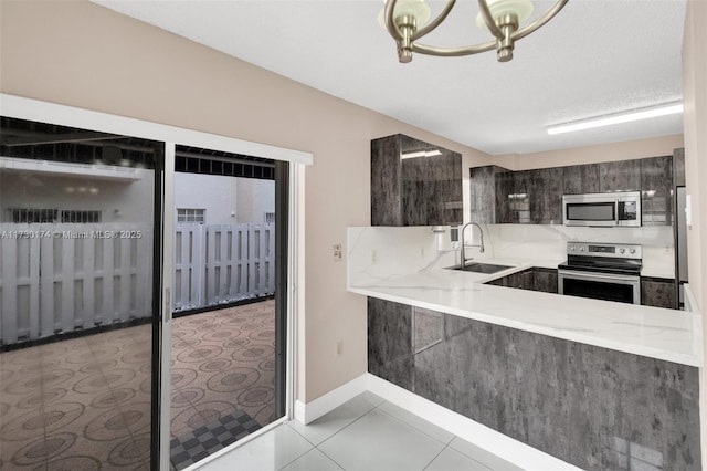 kitchen featuring dark brown cabinetry, sink, light tile patterned floors, kitchen peninsula, and stainless steel appliances