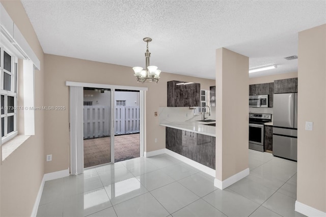 2050 NE 140th St Unit 1, North Miami Beach, FL 33181 - kitchen with appliances with stainless steel finishes, light countertops, a chandelier, a textured ceiling, and a peninsula