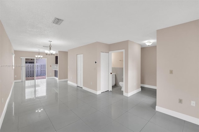 unfurnished room with tile patterned flooring, a notable chandelier, and a textured ceiling