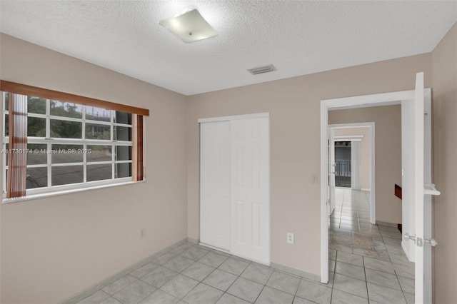 unfurnished bedroom featuring light tile patterned floors, a closet, and a textured ceiling