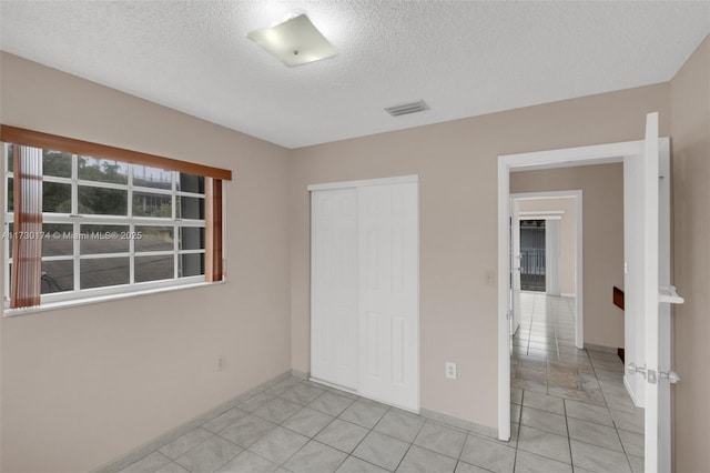 2050 NE 140th St Unit 1, North Miami Beach, FL 33181 - unfurnished bedroom featuring a closet, a textured ceiling, light tile patterned flooring, and baseboards