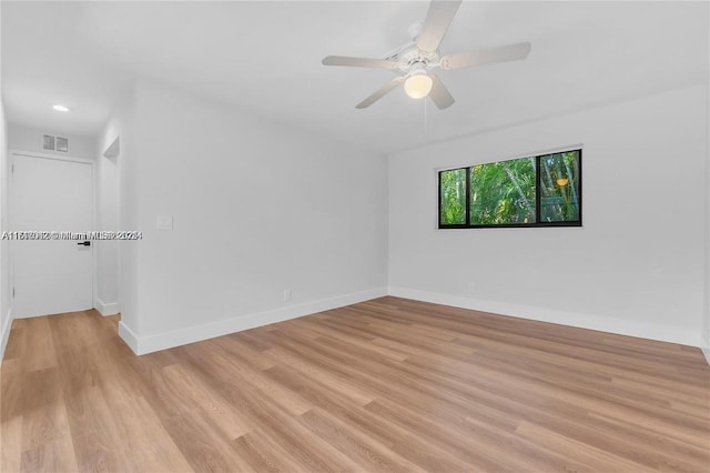 empty room with ceiling fan and light hardwood / wood-style flooring