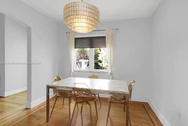 dining room featuring wood-type flooring and an inviting chandelier