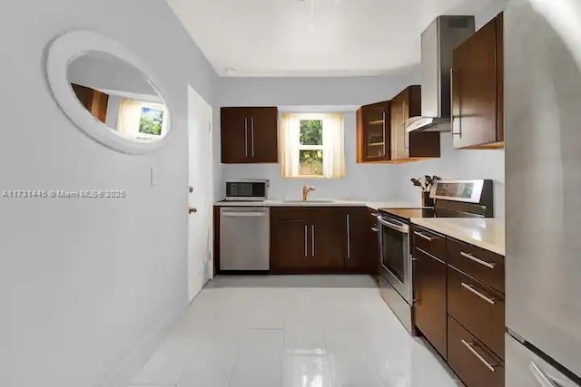 kitchen with wall chimney range hood, light tile patterned flooring, sink, and appliances with stainless steel finishes