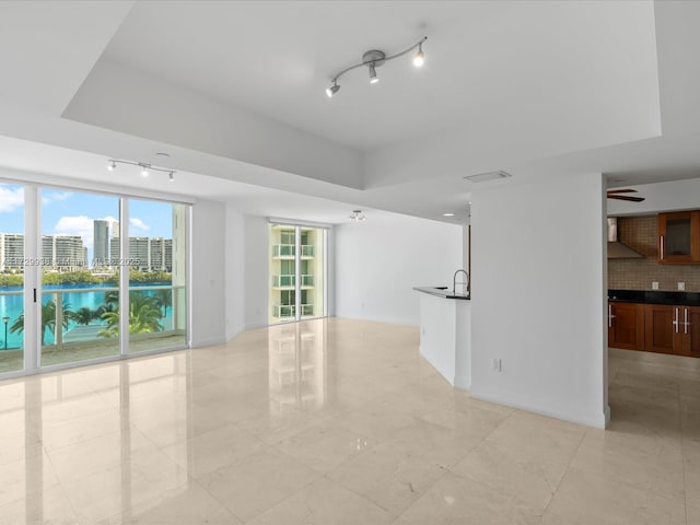 unfurnished living room with a raised ceiling and sink