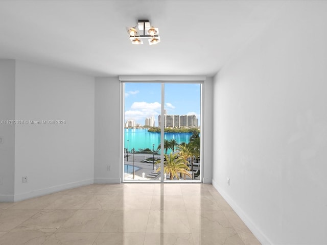 spare room featuring floor to ceiling windows and a water view