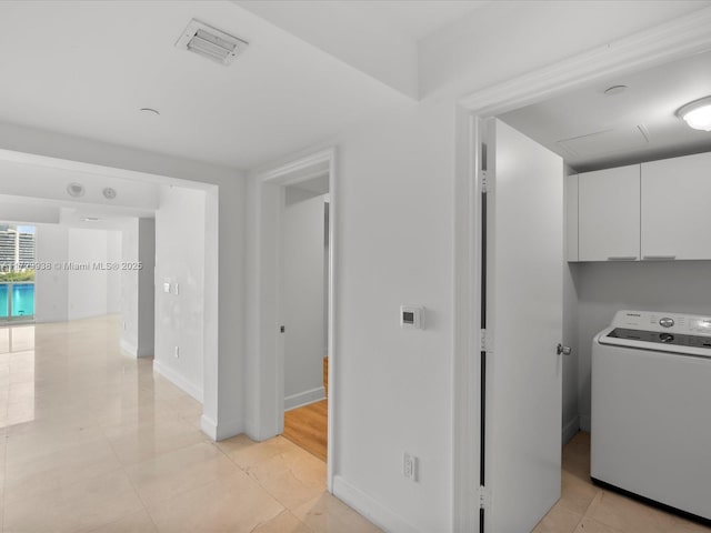 laundry area featuring light tile patterned floors, washer / dryer, and cabinets