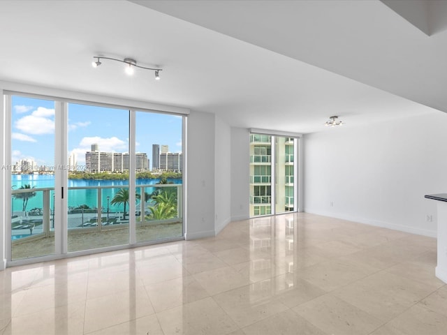 unfurnished room featuring a water view and a wall of windows