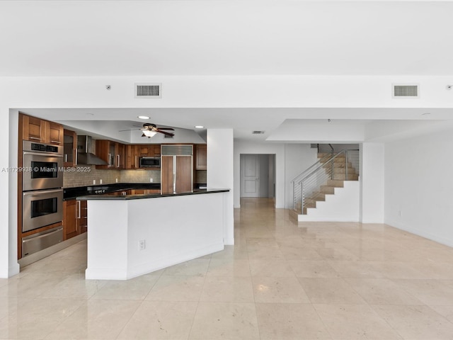 kitchen with backsplash, appliances with stainless steel finishes, and wall chimney range hood