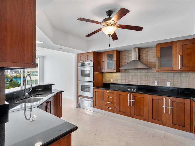 kitchen featuring double oven, tasteful backsplash, sink, black electric stovetop, and wall chimney range hood