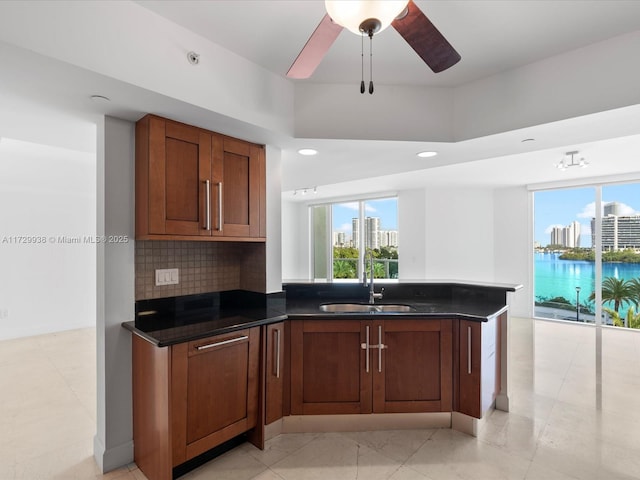 kitchen with a water view, dark stone counters, sink, and tasteful backsplash