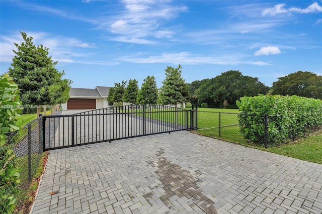 view of gate featuring a garage and a lawn