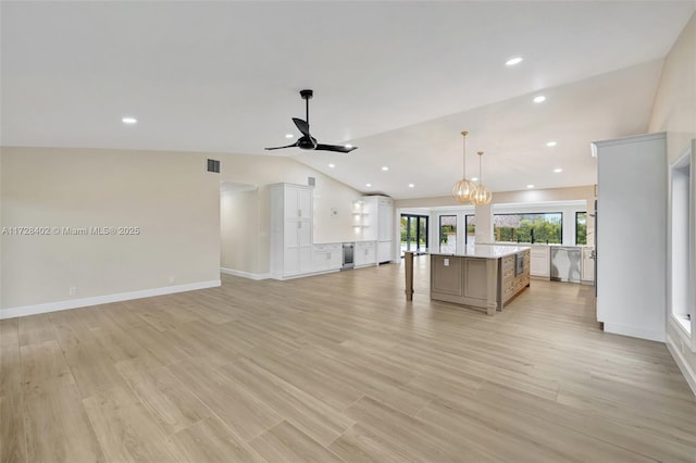 kitchen featuring pendant lighting, lofted ceiling, light hardwood / wood-style flooring, white cabinetry, and a spacious island