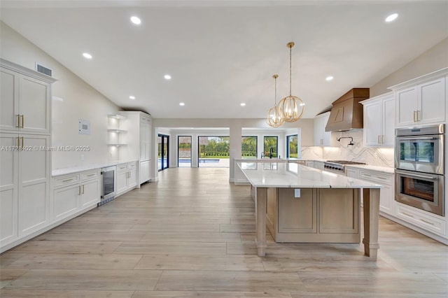 kitchen with white cabinetry, hanging light fixtures, stainless steel appliances, beverage cooler, and backsplash