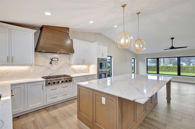 kitchen with lofted ceiling, white cabinets, a center island, stainless steel appliances, and custom range hood