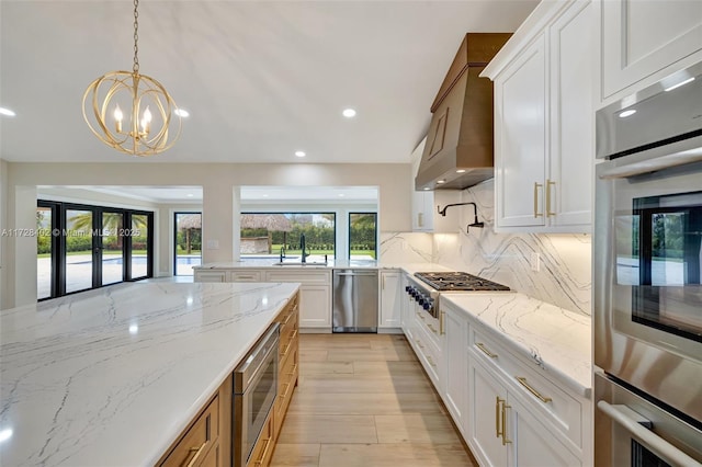 kitchen featuring white cabinetry, premium range hood, light stone counters, and backsplash