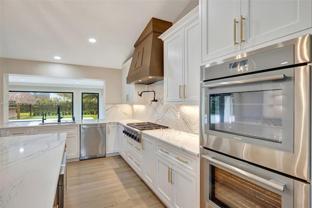 kitchen featuring white cabinetry, appliances with stainless steel finishes, sink, and light stone counters