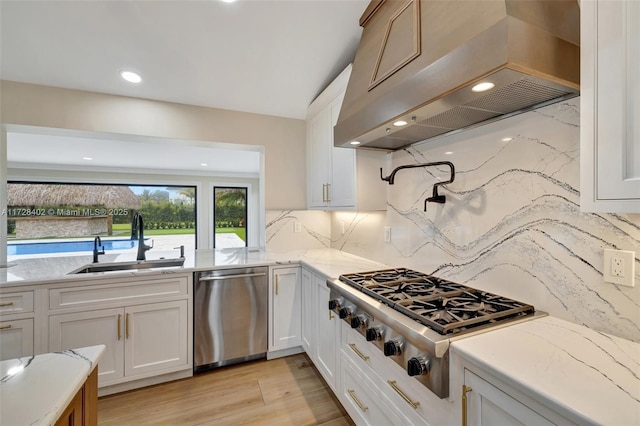 kitchen featuring sink, exhaust hood, stainless steel appliances, decorative backsplash, and white cabinets