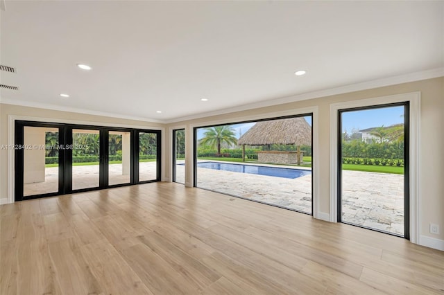 unfurnished living room featuring ornamental molding, light hardwood / wood-style flooring, and plenty of natural light