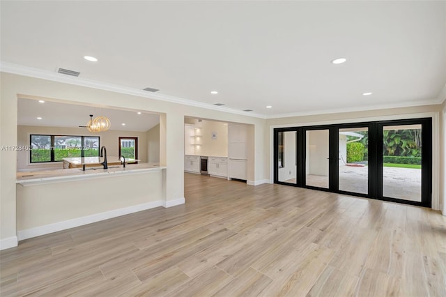 unfurnished living room with light hardwood / wood-style flooring, a wealth of natural light, a chandelier, and french doors