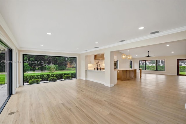 unfurnished living room with sink, crown molding, and light wood-type flooring