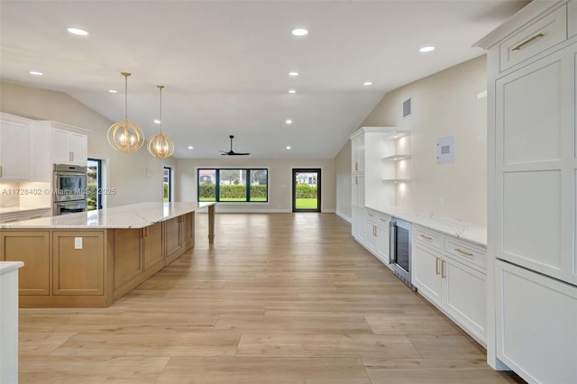 kitchen with white cabinetry, hanging light fixtures, light stone countertops, and lofted ceiling