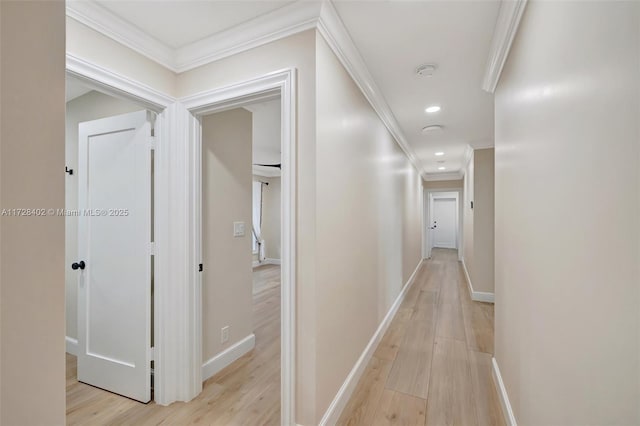 hallway with ornamental molding and light hardwood / wood-style flooring