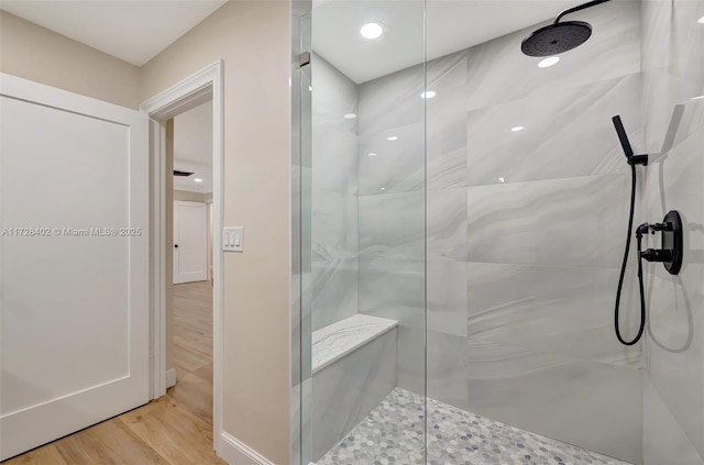 bathroom featuring wood-type flooring and a tile shower