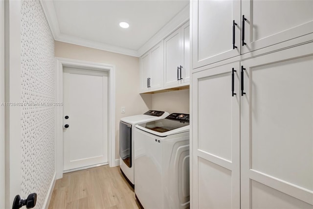 laundry room featuring cabinets, washing machine and clothes dryer, ornamental molding, and light wood-type flooring