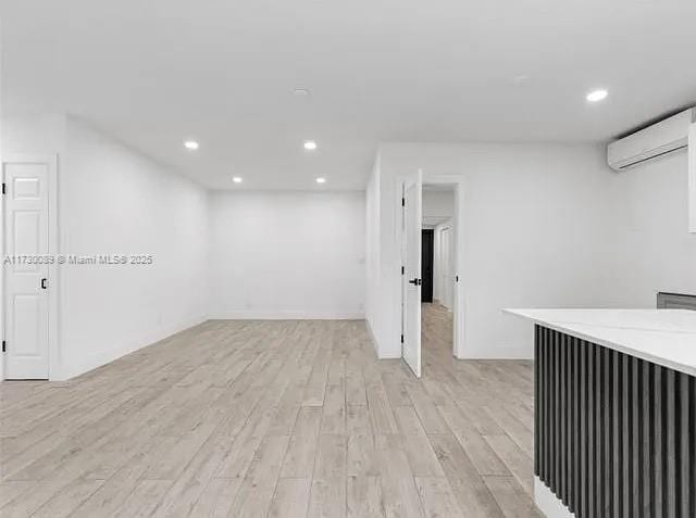 basement with light hardwood / wood-style floors and an AC wall unit