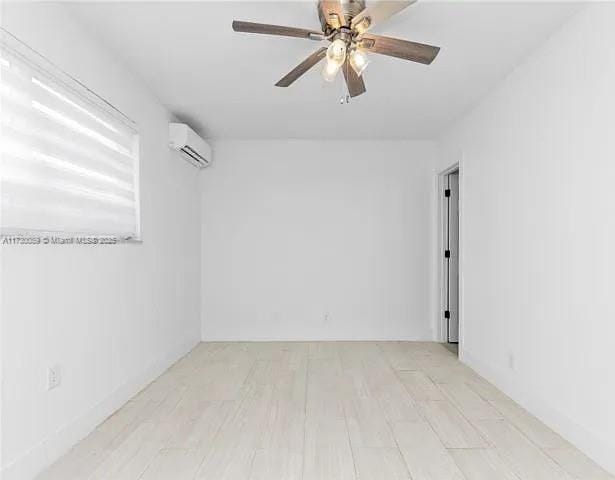 empty room featuring a wall unit AC, ceiling fan, and light wood-type flooring