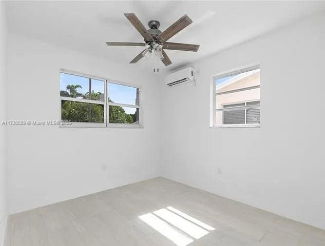 spare room with ceiling fan, light hardwood / wood-style flooring, and an AC wall unit