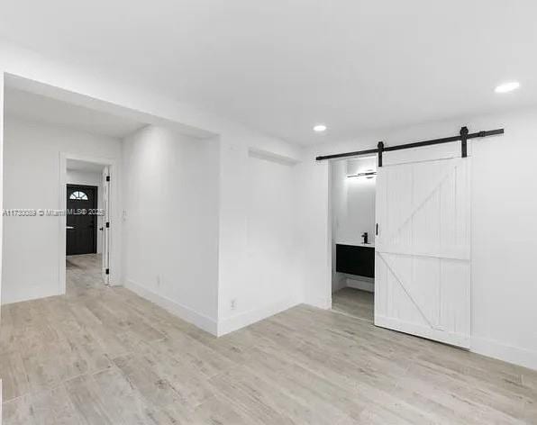 unfurnished room with light hardwood / wood-style floors and a barn door