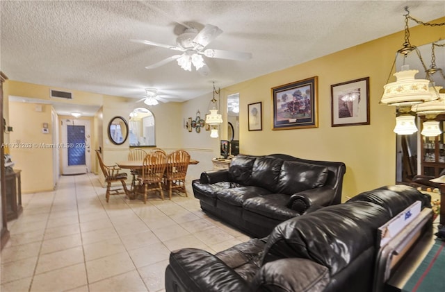 living room featuring light tile patterned floors, a textured ceiling, and ceiling fan