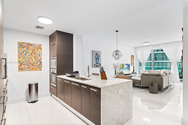 kitchen featuring sink, light tile patterned floors, stainless steel appliances, light stone countertops, and dark brown cabinets