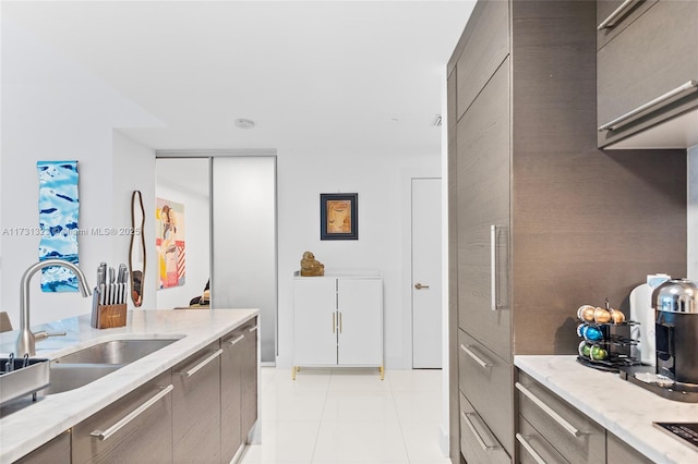 kitchen featuring light stone countertops, sink, and light tile patterned floors