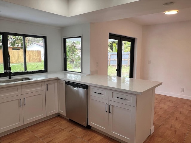 kitchen with sink, white cabinetry, dishwasher, kitchen peninsula, and light stone countertops