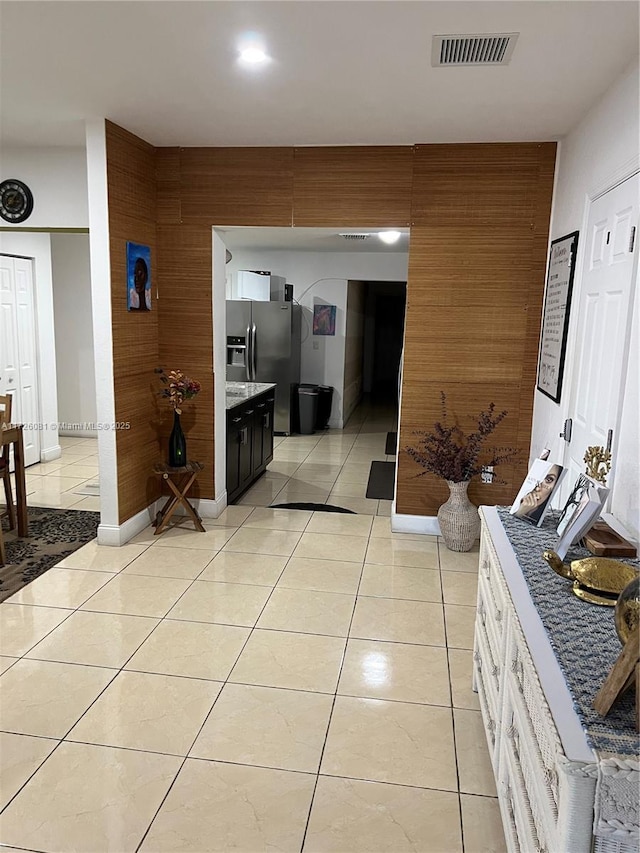 hall with light tile patterned floors and wooden walls